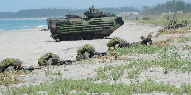Philippine marines take position next to U.S. Marines amphibious assault vehicles during an amphibious landing exercise at the beach of the Philippine navy training center facing the south China sea in San Antonio town, Zambales Province.