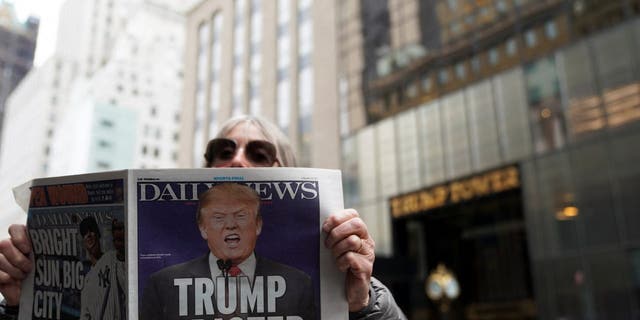 A person poses with a newspaper outside Trump Tower, after his indictment by a Manhattan grand jury, in New York City, March 31, 2023.