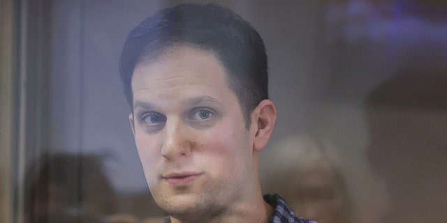 Wall Street Journal reporter Evan Gershkovich, who was detained in March while on a reporting trip and charged with espionage, stands behind a glass wall of an enclosure for defendants before a court hearing to consider an appeal against his detention, in Moscow, Russia April 18, 2023.