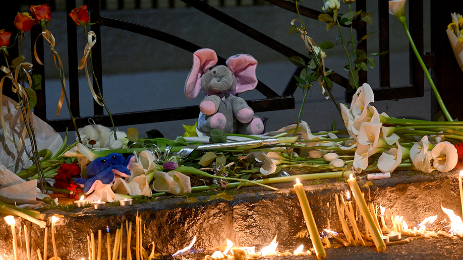 Stuffed elephant left with flowers and candles at a memorial