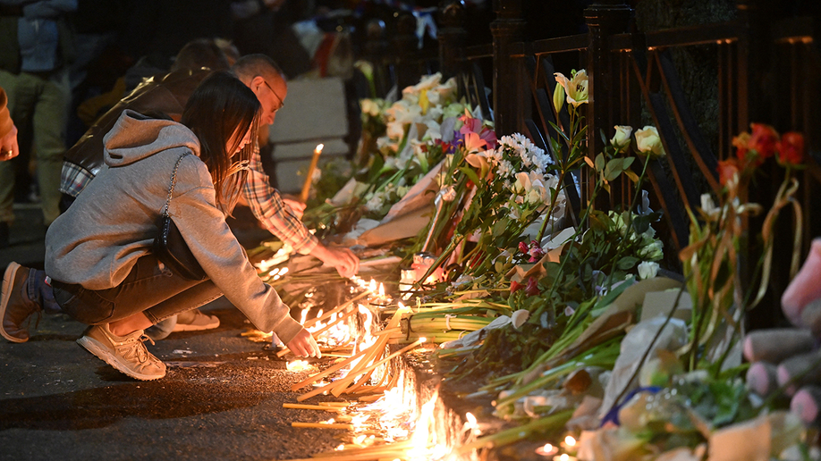 Students lay out candles on a memorial