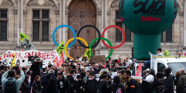 Paris protesters by Olympics sign