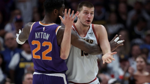 Jokić looks for a foul call while being guarded by Deandre Ayton.
