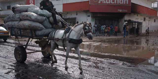 A man drives his horse-drawn cart past a supermarket