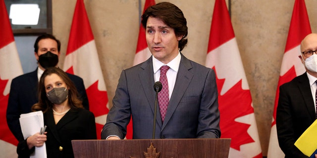 Justin Trudeau at lectern, Canada flags behind him