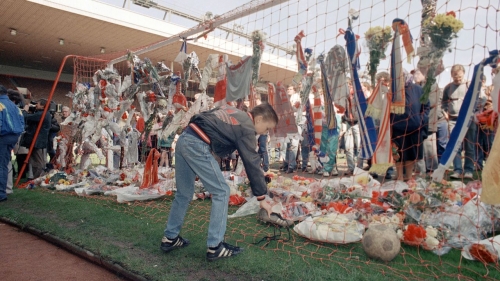 A young Liverpoo fan places a pair of football boots in the goal at the Kop end of Anfield Stadium on April 16, 1989.