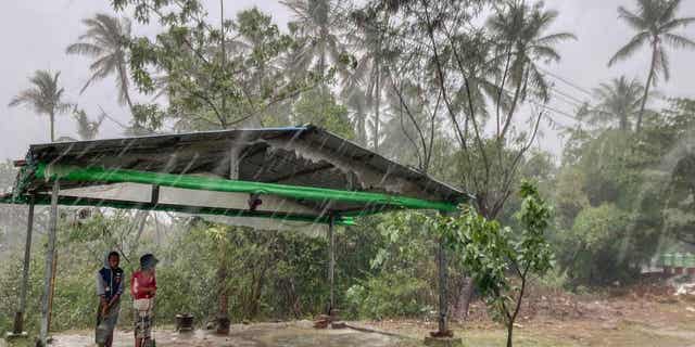 Two children stand under a roadside shelter 