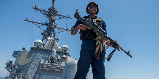US Navy sailor on deck with rifle