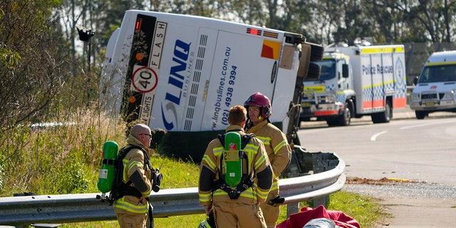 Firefighters standing near a bus crash