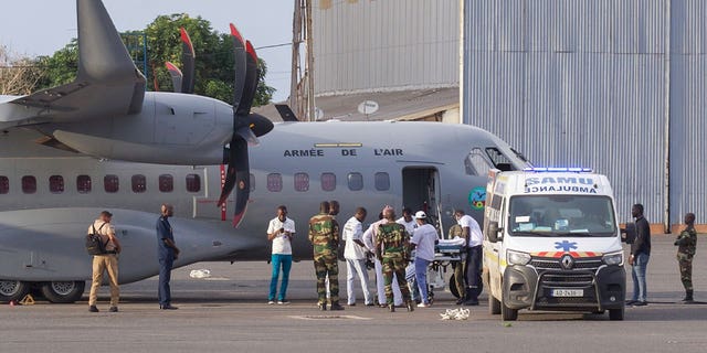 airport personnel transfer migrant survivor into ambulance