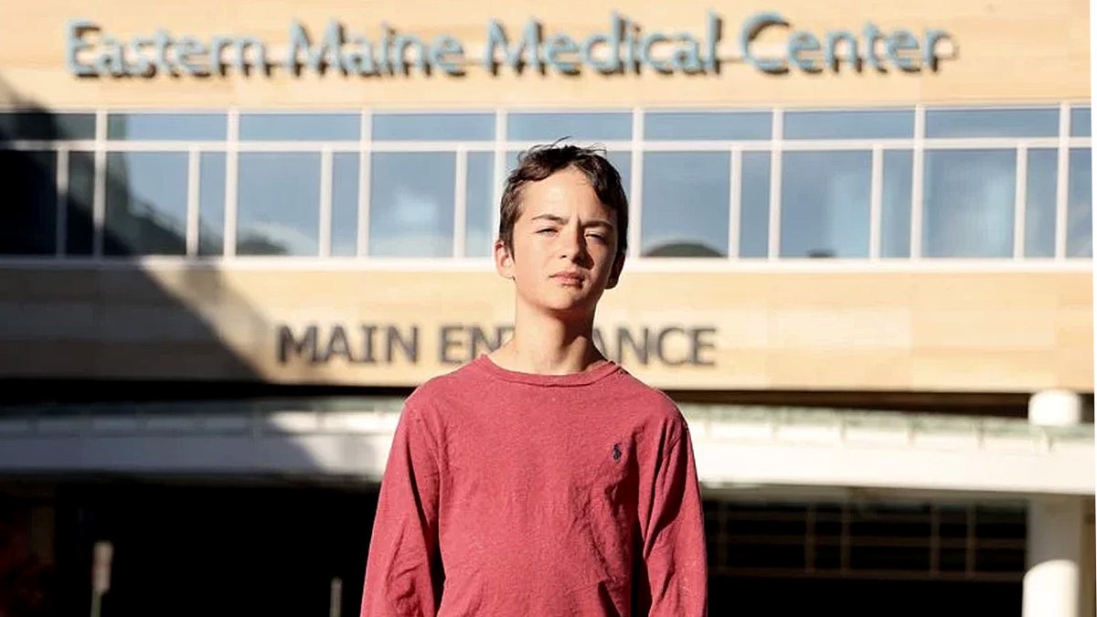 15-year-old Samson Cournane stands in front of hospital building
