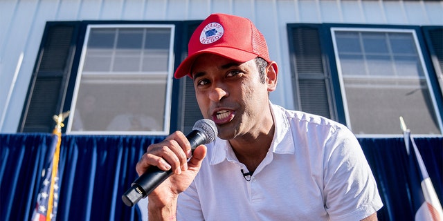 GOP presidential hopeful Vivek Ramaswamy in red cap, white shirt holding microphone