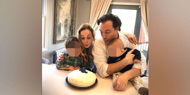 Ana and Brian hold their children and blow out birthday candles