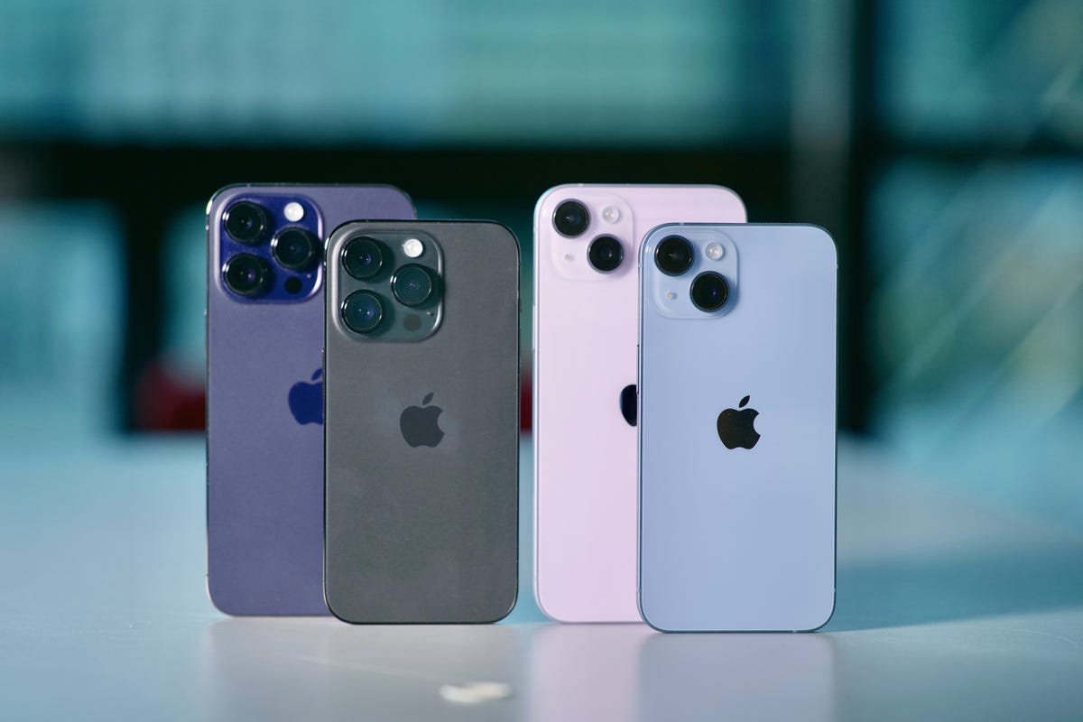 All four models in the iPhone 14 series standing on a desk
