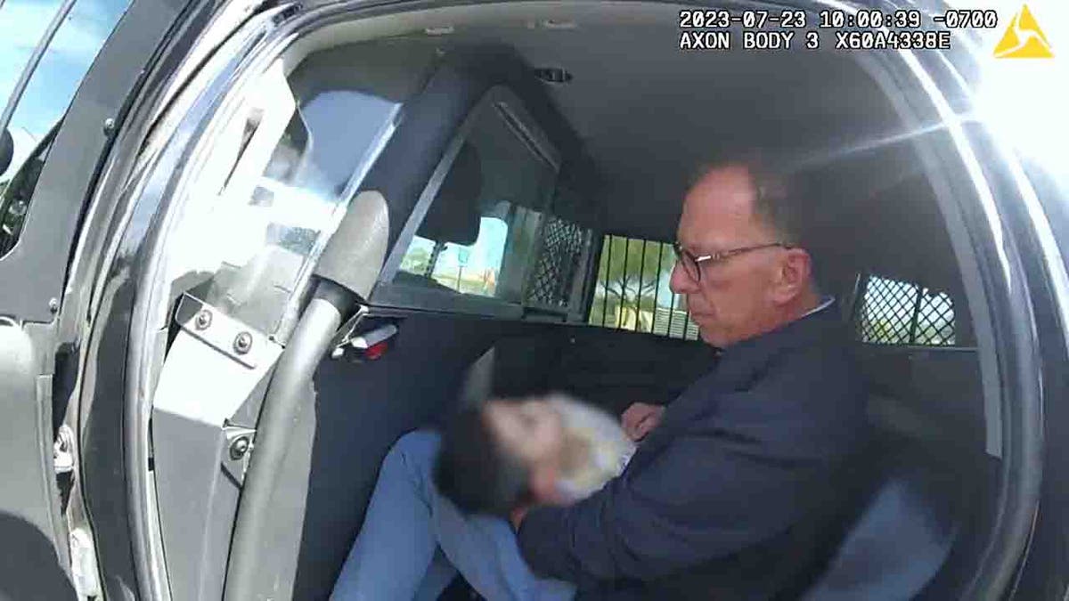 retired paramedic holding baby in police car