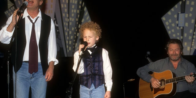 Art Garfunkel Jr. and his son on stage singing wearing identical outfits