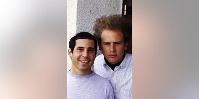 Paul Simon and Art Garfunkel leaning close to each other for a photo