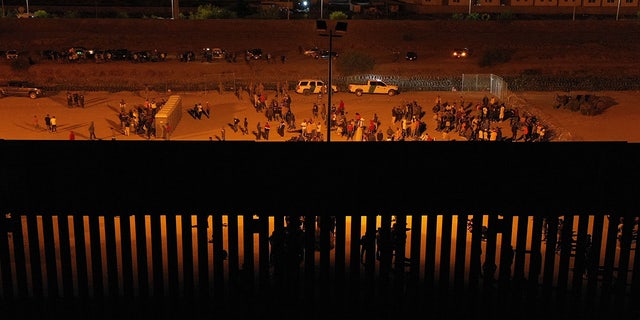 Crowds of migrants by Texas border wall