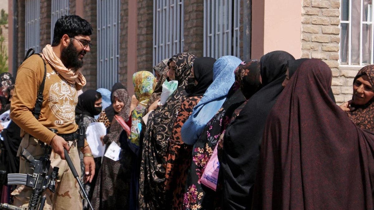 Women stand in a queue outside the passport office in Herat