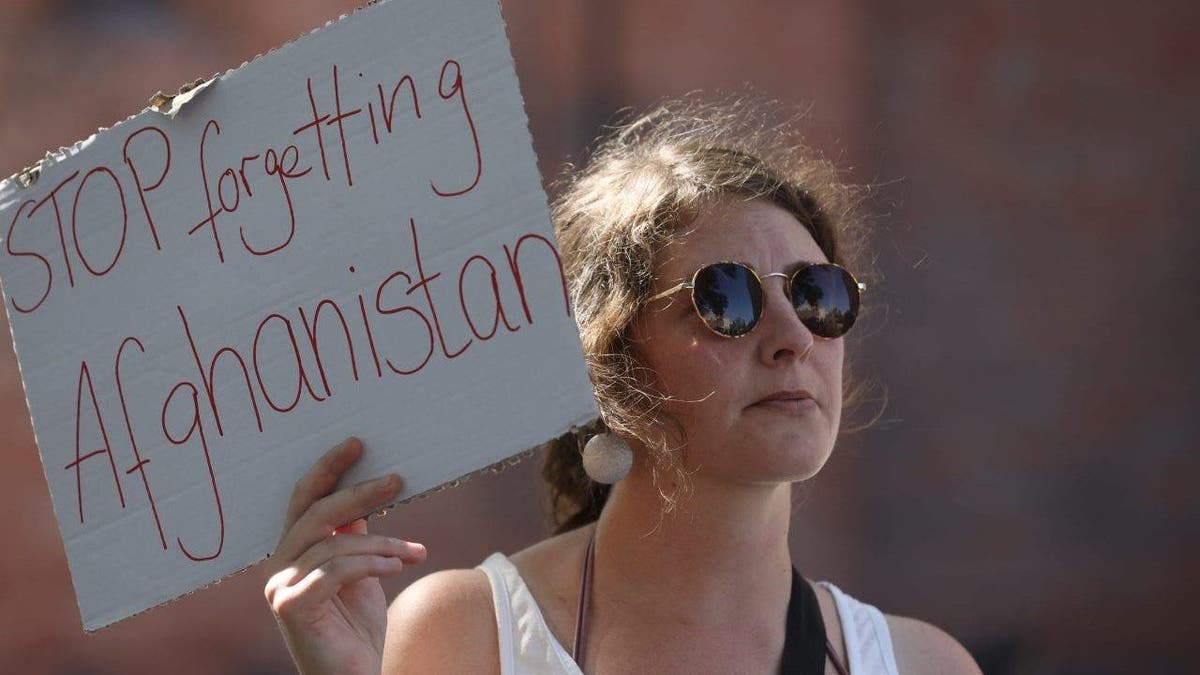A protester with a sign reading "Stop Forgetting Afghanistan"