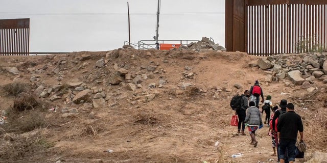 Migrants walking toward border wall gap