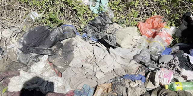 Piles of clothes and trash on the riverbank near U.S. border
