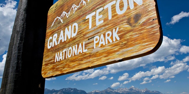 A sign for Grand Teton National Park with mountains in the background