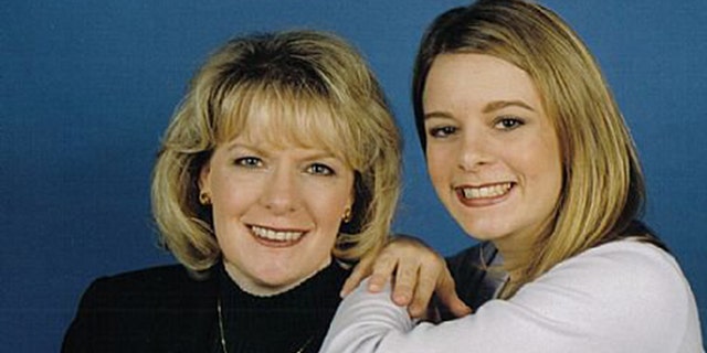 Christie Wilson wearing a white long sleeved sweater posing next to her mother in a black turtleneck sweater