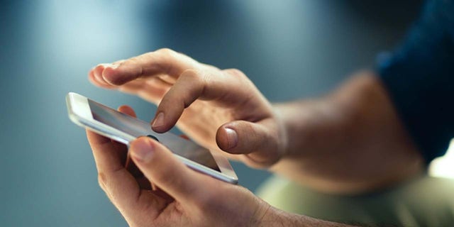 Man holds smartphone and touches screen