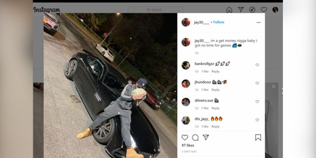 Screenshot of a social media post showing a man holding a large quantity of cash while sitting on the hood of his car.