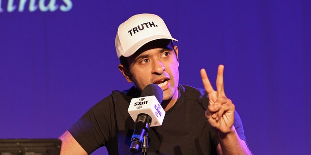 Ramaswamy in black shirt, white "truth" cap, speaking into microphone