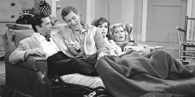 The cast of the Dick Van Dyke Show laying together in one couch looking surprised