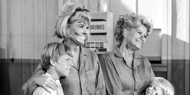 Doris Day and Rose Marie wearing dirty jumpsuits as they embrace two child actors