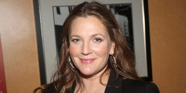 Drew Barrymore soft smiles in a black jacket with large hoop earrings in New York