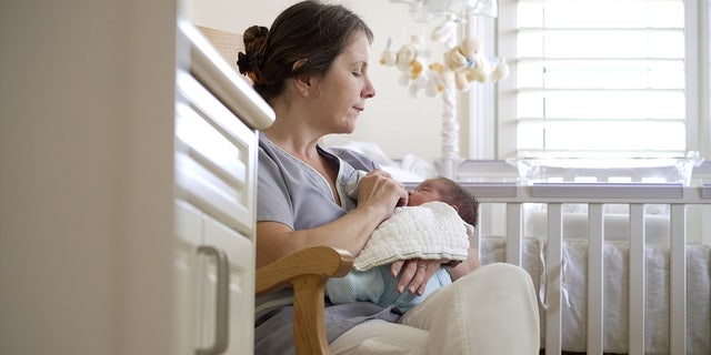 Woman in rocking chair feeds baby