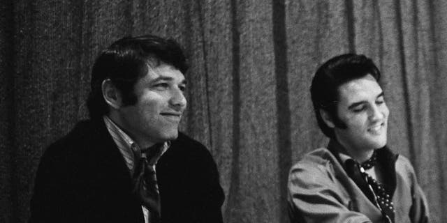 A close-up of Steve Binder and Elvis Presley sitting together and smiling