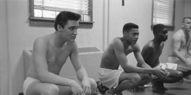 Elvis Presley squats while waiting for exams in the Army