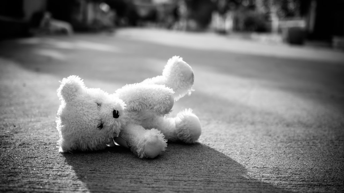 Stuffed bear lies on the ground