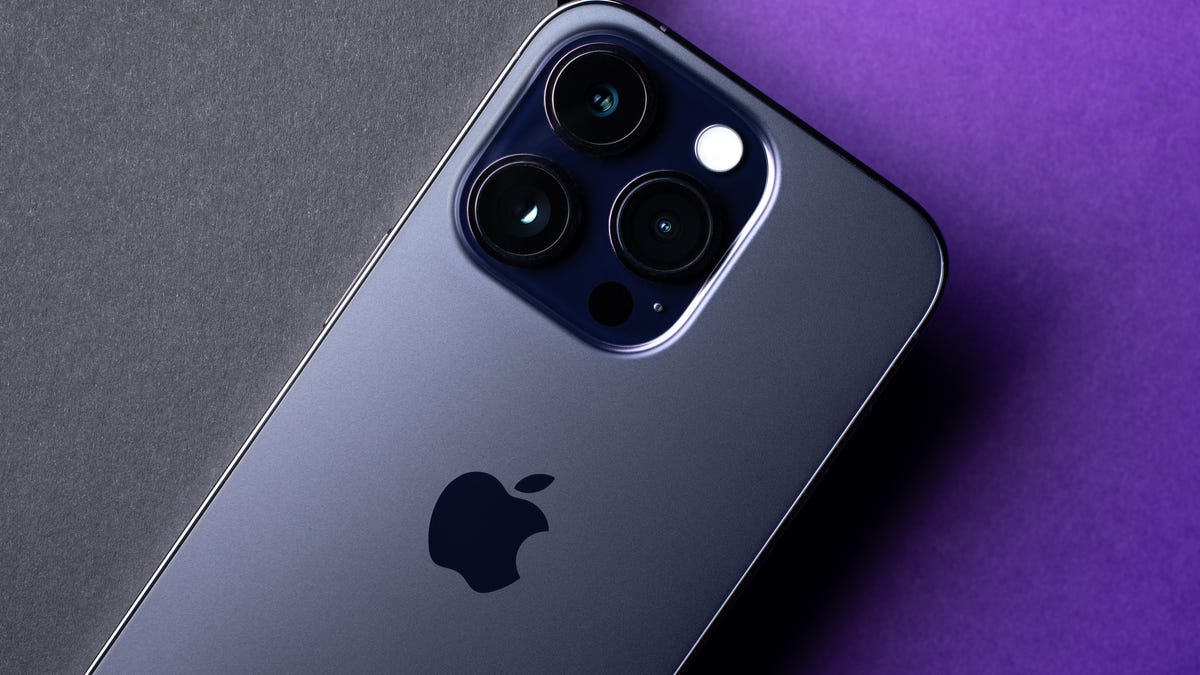 iPhone 14 Pro against a deep purple and gray background