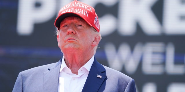 Donald Trump in red MAGA hat, blue coat