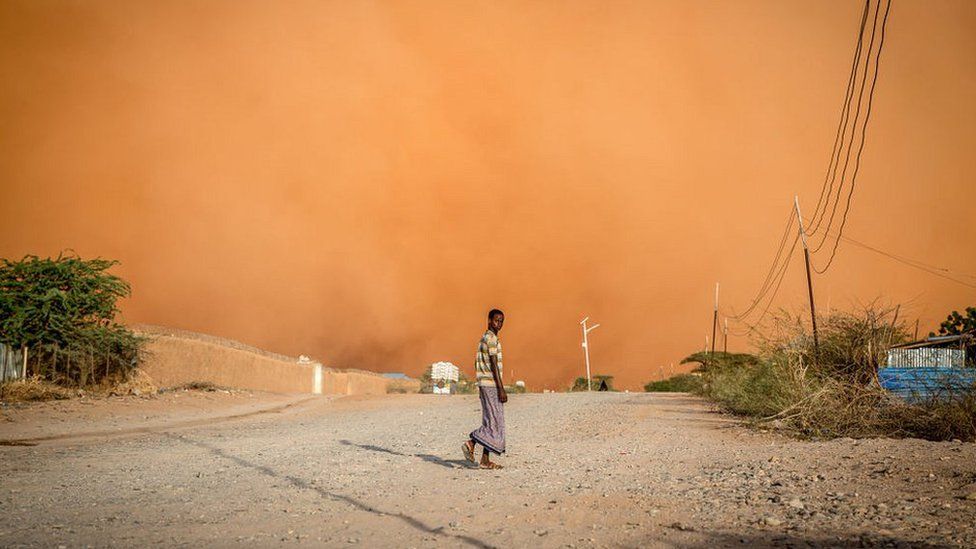 A man walks in front of a sandstorm in Dollow, southwest Somalia. People from across Gedo in Somalia have been displaced due to drought. 14 April 2022.