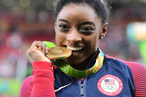 Biles celebrates with the gold medal she earned for her individual all-around title at the 2016 Olympics.