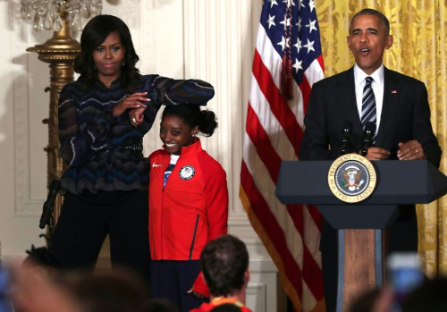 First lady Michelle Obama rests her elbow on Biles' head as President Barack Obama speaks at the White House in September 2016. The Obamas were hosting an event for US Olympians.