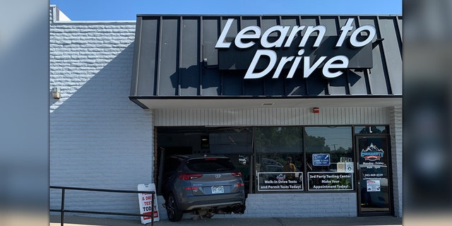 Car crashed into building under "Learn to Drive" sign