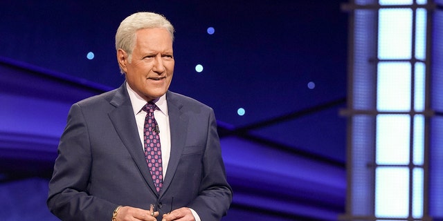 Alex Trebek in a dark suit and purple tie on "Jeopardy"