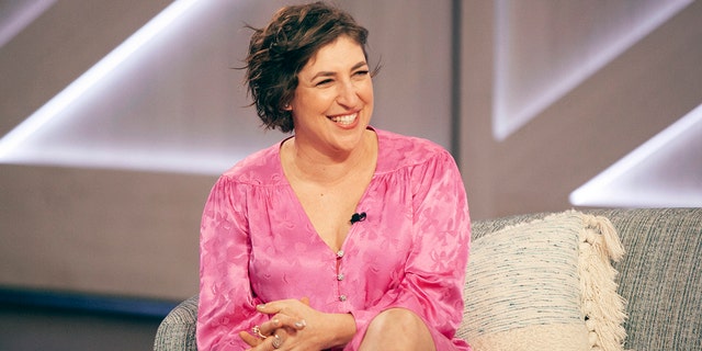 Mayim Bialik sitting on a couch