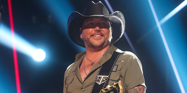 Jason Aldean wears black cowboy hat on stage while performing
