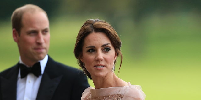 Kate Middleton wearing a pale pink dress next to Prince William in a tux
