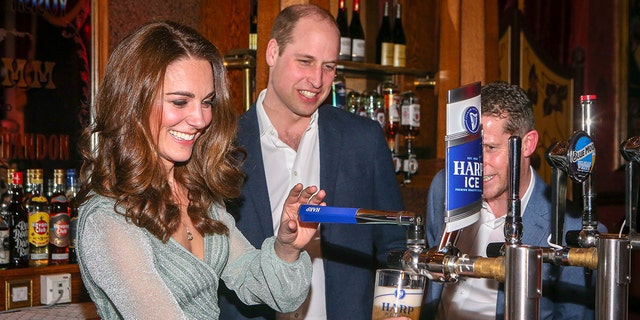Kate Middleton wearing a pale green dress working the bar as prince william watches