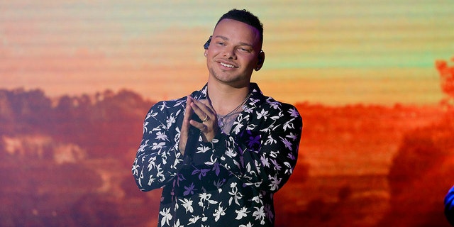 Kane Brown holds microphone on stage